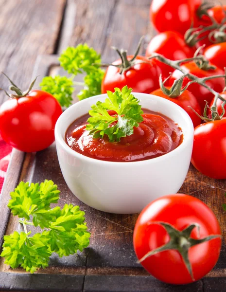 Tigela de molho de tomate e tomate cereja na mesa de madeira . — Fotografia de Stock