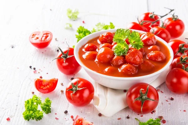 Miska z sosem pomidorowym i pomidorkami na drewnianym stole. — Zdjęcie stockowe