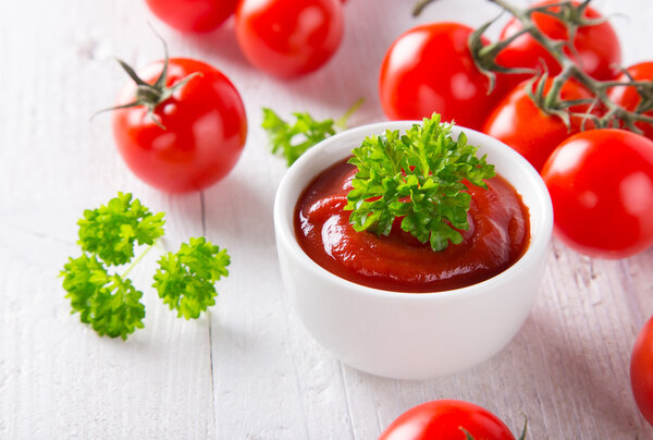 Чаша томатного соуса и помидоры черри на деревянном столе
.