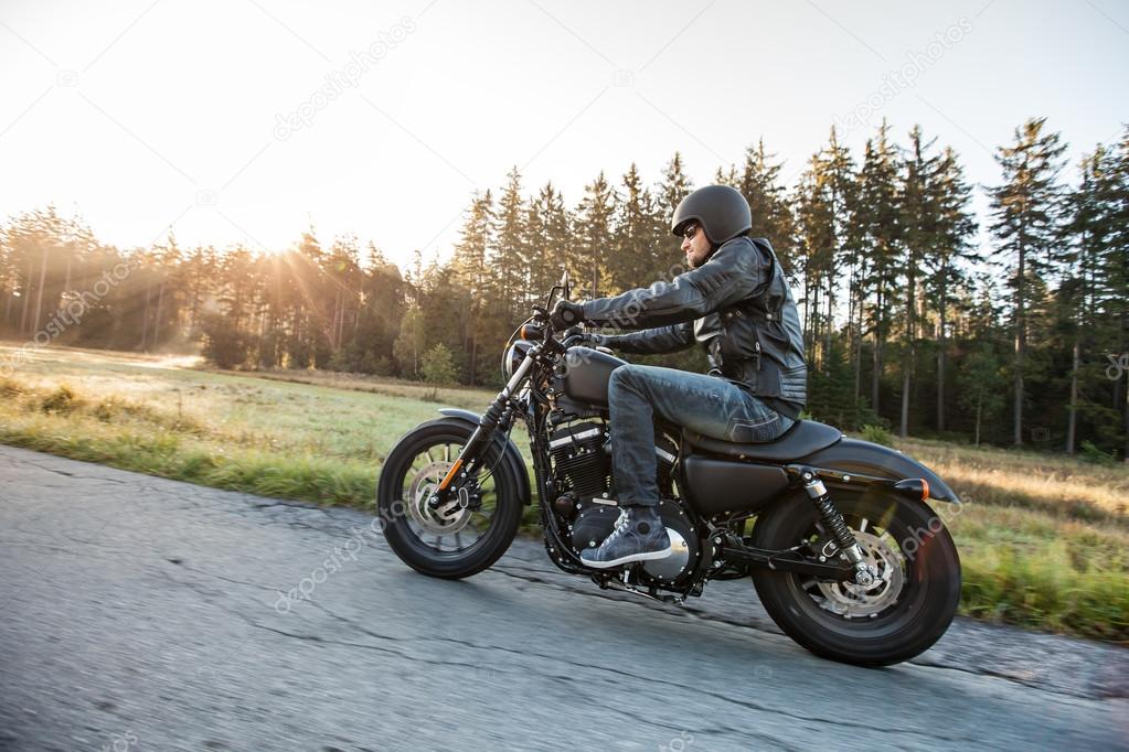 Man seat on the motorcycle on the forest road.