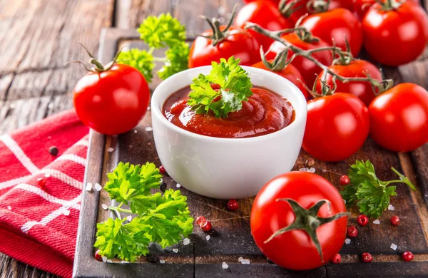 Tigela de molho de tomate e tomate cereja na mesa de madeira . — Fotografia de Stock