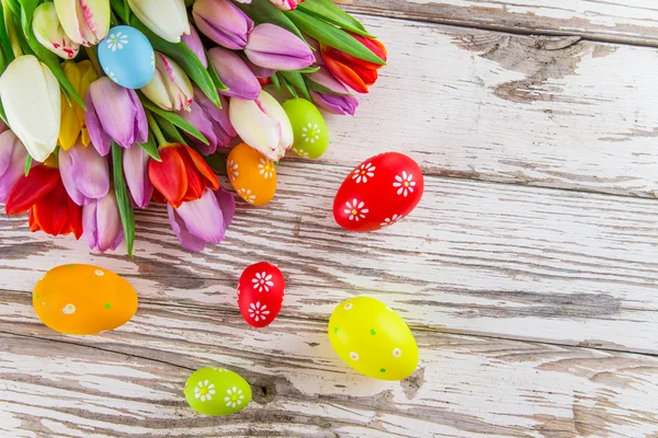 Tulipanes coloridos con huevos en mesa de madera . — Foto de Stock