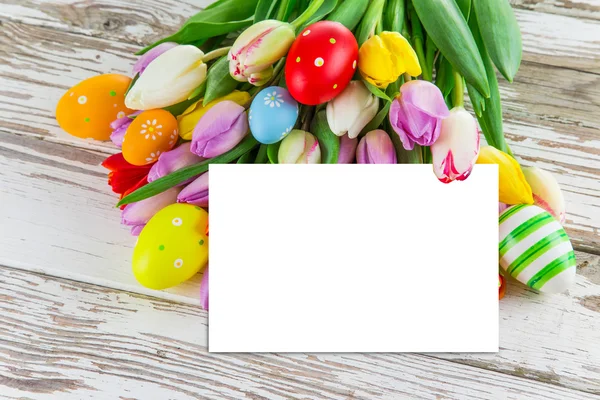 Colorful tulips with eggs on wooden table. — Stock Photo, Image