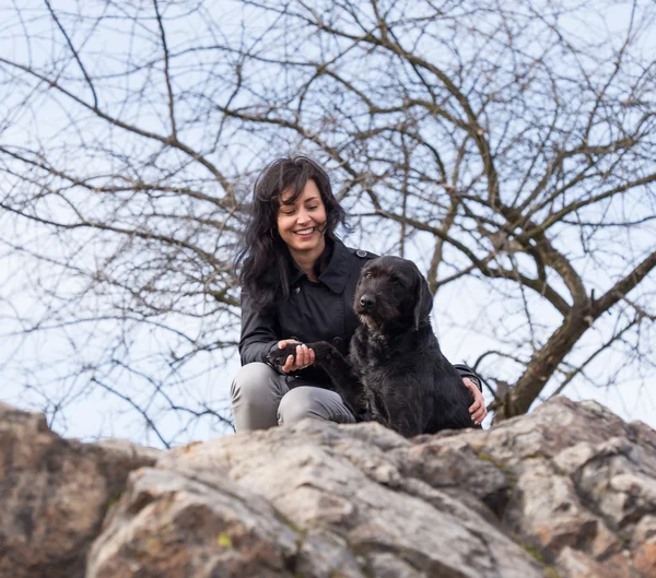 Beautiful girl with mutt black dog on mountains — Stock Photo, Image