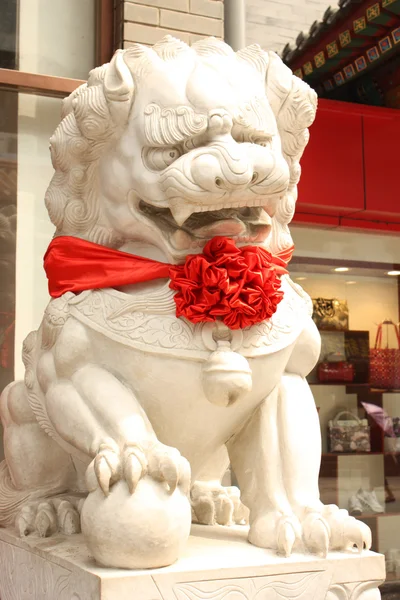 León de piedra con un lazo rojo en una calle de Beijing —  Fotos de Stock