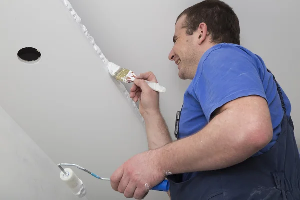 Painter painting a house ceiling with brush and roller — Stock Photo, Image