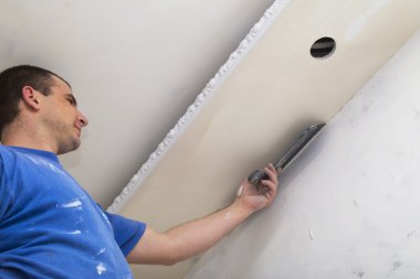 Man worker applying the layer of putty with trowel clipart