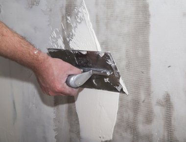 İnşaatçılar float el duvarın üzerinde macun uygulama