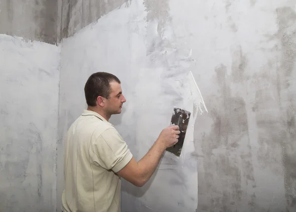 Uomo lavoratore che applica il primo strato di stucco con spatola — Foto Stock