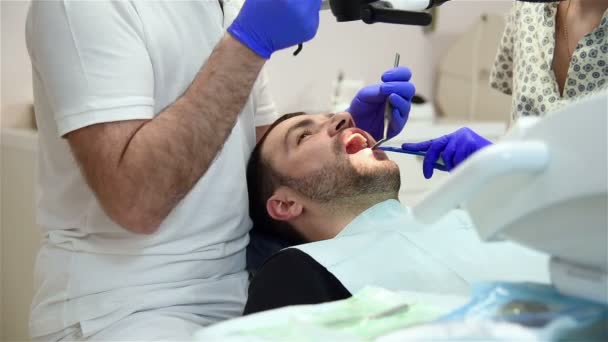 Dentista que trata a un paciente masculino — Vídeos de Stock