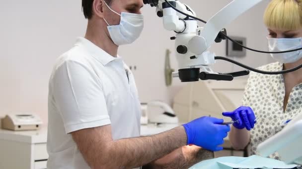 Стоматолог лікує пацієнта, помічник допомагає йому — стокове відео