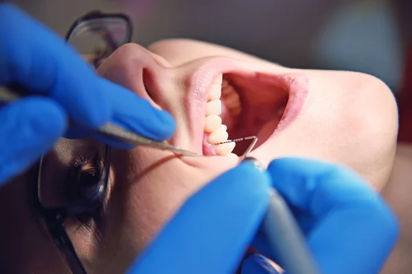 Дантист осматривает зубы пациента — стоковое фото
