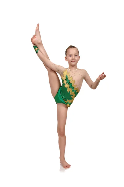 Malá dívka gymnastka v zelených šatech vzbudil její nohu — Stock fotografie