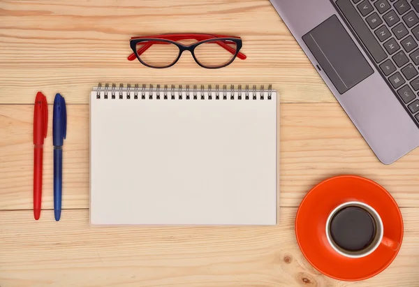 Tom anteckningsbok och materiella office desktop på trä skrivbord, ovanifrån. — Stockfoto