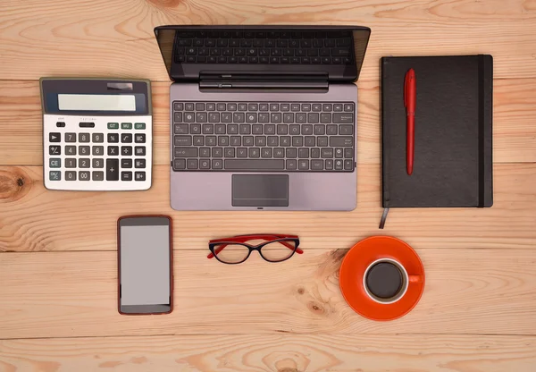 Open laptop, cellphone, glasses, calculator and cup of coffee on wooden table — Stock Photo, Image