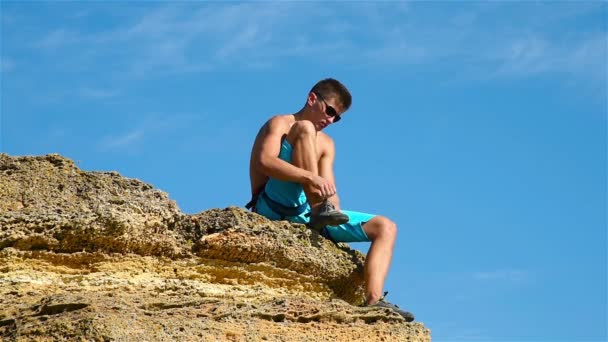 Extremo alpinista coloca sapatos sentados em uma rocha — Vídeo de Stock