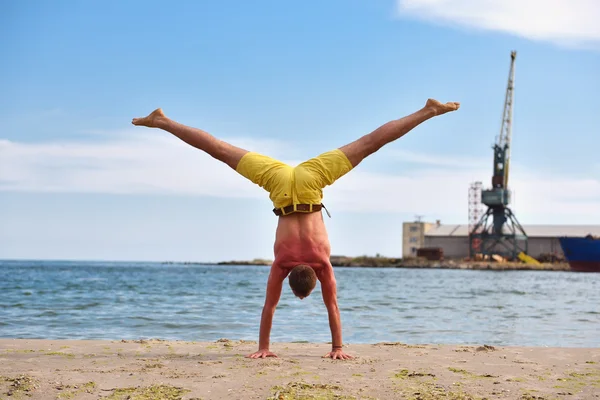 Junger Mann praktiziert Yoga am Strand — Stockfoto