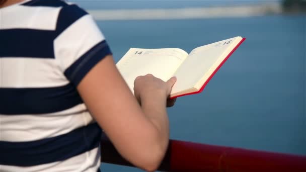流行に敏感な女の子の手は、赤い本を保持します。スローモーション効果 — ストック動画