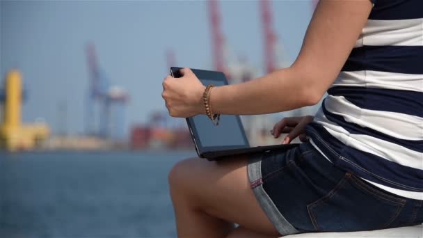 Dívka, psaní na notebooku v přístavu. Efekt zpomaleného pohybu — Stock video