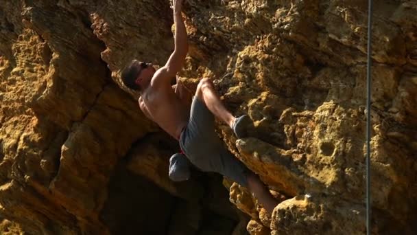 Мускулистый альпинист взбирается на желтую скалу без страховки — стоковое видео
