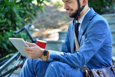 Merdivenlerde oturup dijital tablet kullanan mutlu sakallı iş adamı. İş ve alternatif ulaşım kavramı