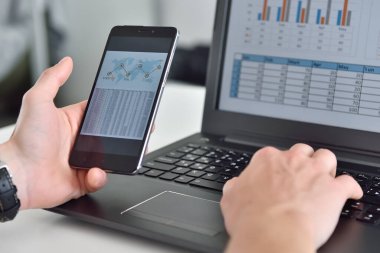 Finansal bilgili akıllı telefonu elinde tutan bir iş adamı. İş ve finansal konsept. Kapat.