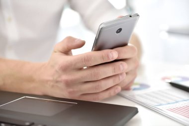 Borsa komisyoncusu cep telefonu kullanıyor ve rapor verilerini kontrol ediyor. Finans ve ticaret konsepti. Kapat.