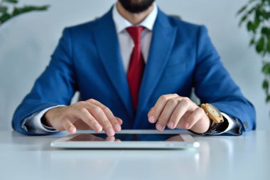 Genç işadamı, hisse senedi raporu ve mali verileri içeren tablet bilgisayar kullanıyor. İş ve başarı kavramı.