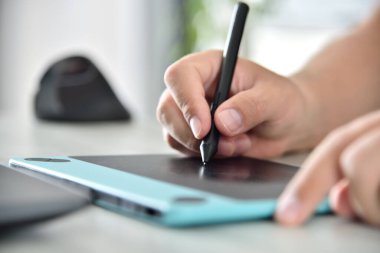 Grafik tasarımcısı grafik tablet kullanıyor. Uzaktan çalışma ve tasarım konsepti. Kapat.