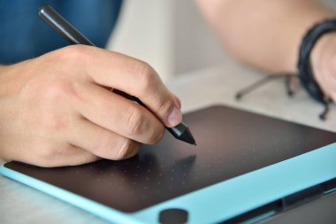 Tasarımcı elleri, ofisteki dijital grafik tabletine çizim yapıyor. Uzaktan çalışma ve tasarım konsepti. Kapat.
