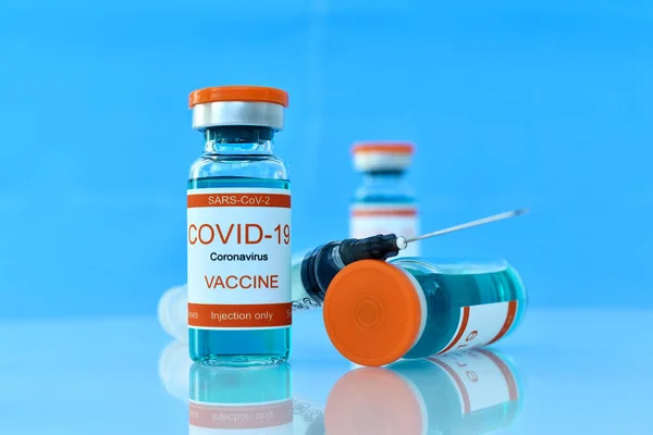 Covid-19 vaccine and syringe injection on blue table. Healthcare and corona virus vaccination concept. Close up.