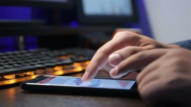 Başlangıç istatistikleri ve hisse senedi verileriyle akıllı telefon kullanan bir işadamı. İş ve Mali Başarı Konsepti. Yavaş Hareket Etkisi. Kapat.