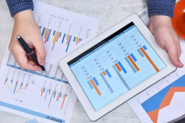 Tablet ve mali belge kullanan tüccarların üst görüşü. Para ve ticaret konsepti. Kapat.