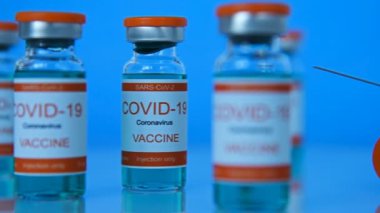 Covid-19 Coronavirus Aşısı ve Mavi Arkaplanda Şırınga Enjeksiyonu. İlaç ve Corona Virüs Enfeksiyonu. Yavaş Hareket Etkisi. Kapat.