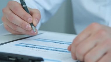 Kalem yazan erkek doktor hastanedeki panoya tıbbi rapor yazıyor. Tıp ve Sağlık Hizmetleri Konsepti.