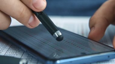 Stylus 'la birlikte cep telefonu ekranında istatistikleri izleyen bir iş adamı. İnternet Ticareti ve Stok İstatistikleri Konsepti. Yavaş Hareket Etkisi. Kapat.