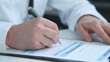 Hastanedeki panoya kalem ile tıbbi rapor yazan bir doktor. Tıp ve Sağlık Hizmetleri Konsepti. Kapat.