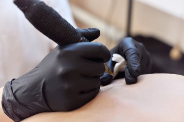 Kadın dövmeci sırtına dövme yaptırıyor. Sanat ve tasarım konsepti. Kapat.