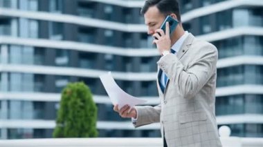 Akıllı telefondan konuşan ve iş sözleşmesini elinde tutan bir iş adamı. İş ve Bilgi Teknolojisi Konsepti. Yavaş Hareket Etkisi. Kapat.