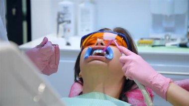 Diş hekimi diş beyazlatma prosedüründen önce dişlerini beyazlatan jel kalıntılarından temizler. Sağlık ve Tıp Konsepti 'nden. Kapat.