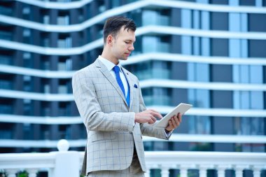 Modern şehir arka planında dijital tablet bilgisayar kullanan bir iş adamı. İş ve teknoloji kavramı. Kapat.