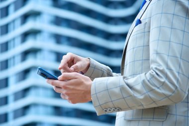 Takım elbiseli bir işadamı elinde akıllı telefon kullanıyor. İş ve teknoloji kavramı. Kapat.