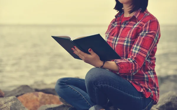 Meisje, zittend op een rots en lezen van een boek — Stockfoto