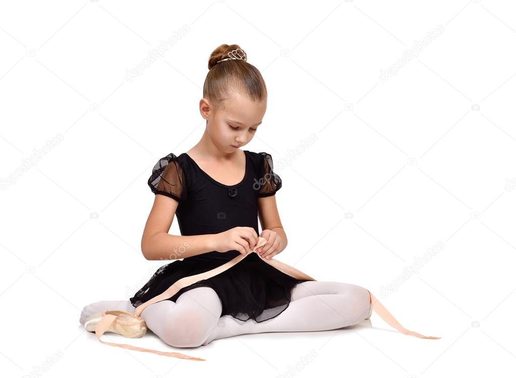 little ballerina sitting on floor wears pointe shoes