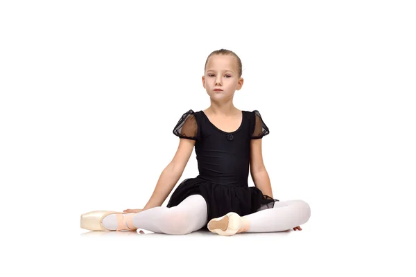 Маленькая балерина сидит на полу в черной пачке — стоковое фото