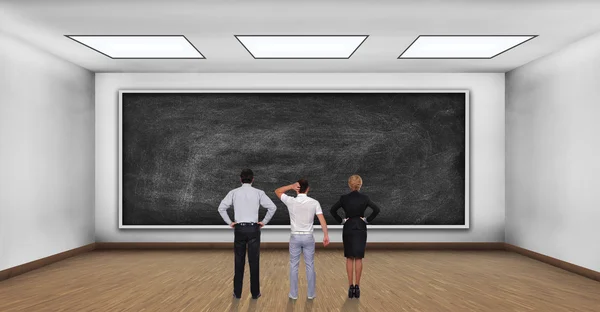 Three businesspeople looking on blank black board — Stock Photo, Image