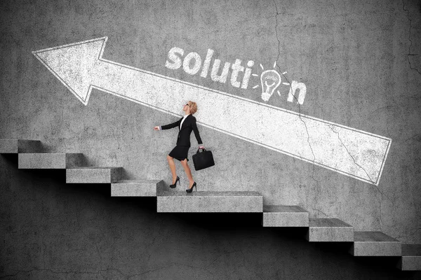 Businesswoman with briefcase walking up on stairs. Drawing white arrow on wall. Solution concept — Stock Photo, Image