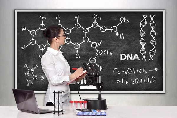 Wetenschappelijk onderzoeker van de vrouw in het laboratorium en op zoek op blackboard met het opstellen van chemische regeling — Stockfoto