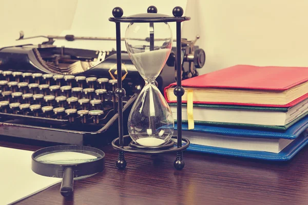 Песочные часы, книги и старинная пишущая машинка — стоковое фото