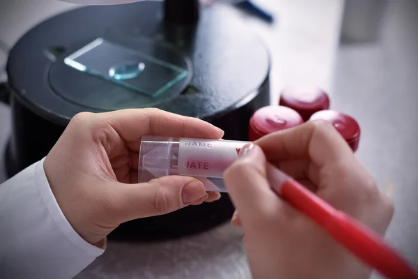 Femme scientifique signe récipient échantillons — Photo